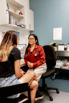 ENT doctor listening to her lady patient in her office