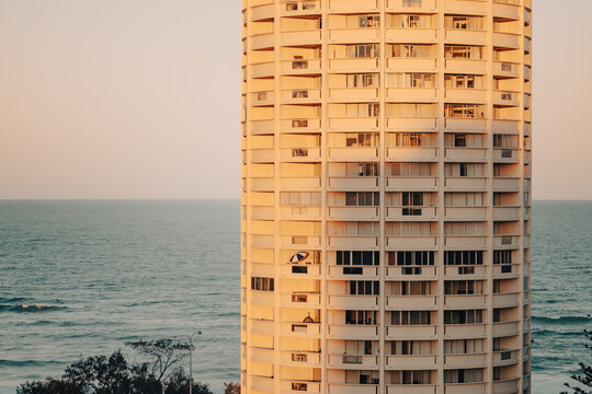 Modern cylindrical apartment building facade overlooking the ocean at sunset