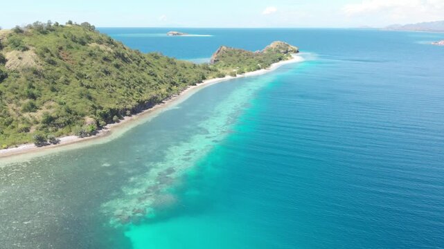 Panoramic aerial view of the 17 Islands Marine Park near Riung, Flores, Indonesia, featuring turquoise coral reefs, tropical islets, and deep blue ocean under a bright sky