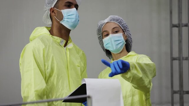 Supervisory team wearing PPE meticulously inspects the mackerel or sardine production line from canning to tomato sauce filling on conveyor belts in industrial seafood processing plants.