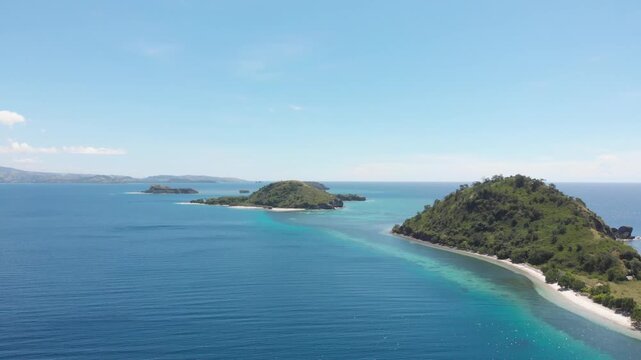 Panoramic aerial view of the 17 Islands Marine Park near Riung, Flores, Indonesia, featuring turquoise coral reefs, tropical islets, and deep blue ocean under a bright sky