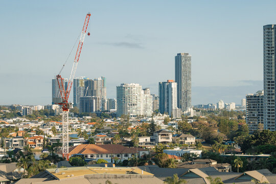 Construction crane overlooks a developing city skyline with residential and high-rise buildings