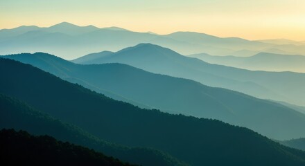 Obraz premium Majestic Layered Blue Mountain Ridges at Sunrise with Misty Atmosphere and Golden Sky