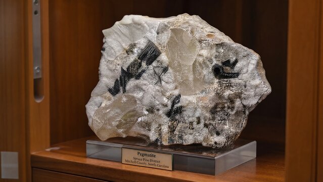 pegmatite. Pegmatite specimen displayed in a wooden mineral collection cabinet. STEM education sheets, lab safety posters, designed for biotech research communications, used by fitness trainers.