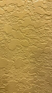 Yellow Knockdown Drywall Texture Background. Gold colored rough stucco wall texture backdrop. Close-up of yellow stucco wall plaster finish.