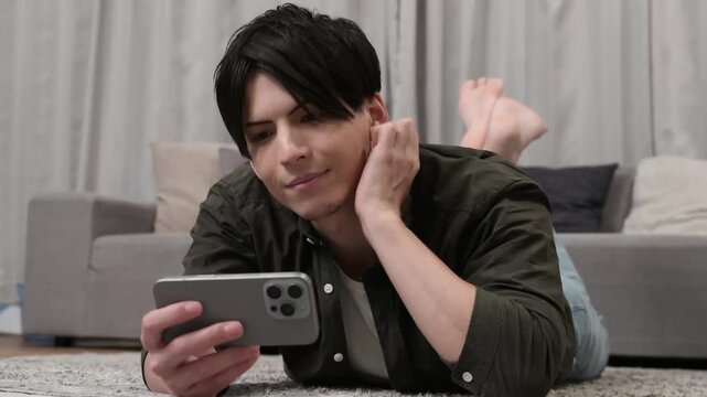 うつ伏せでスマホを見る男性