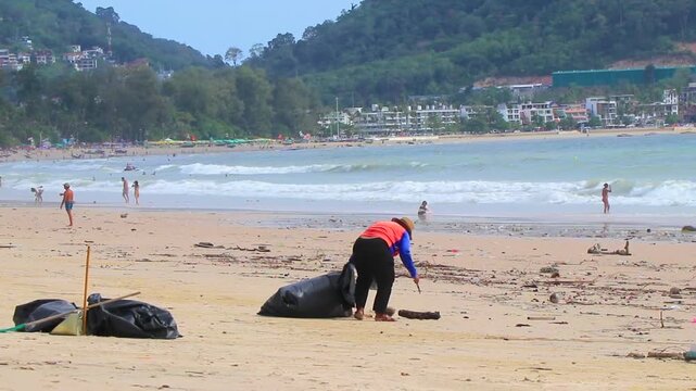 Thai locals cleaning massive ocean trash from polluted tropical Patong Beach Thailand.