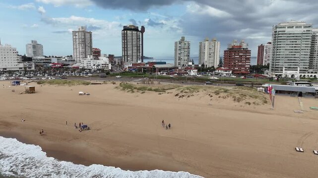 PUNTA DEL ESTE, URUGUAY: Aerial drone view of Playa Brava beach featuring the famous Fingers Sculpture on the sand, with Atlantic ocean waves and beachfront luxury high-rise buildings.