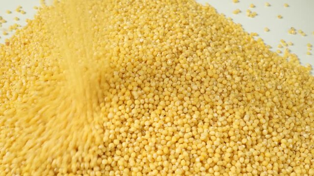 Pouring heap of millet grains on white background