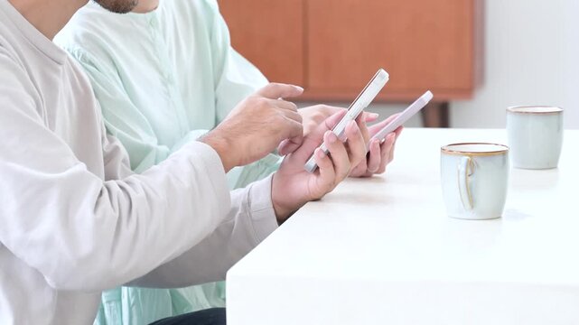 リビングでスマホを見る日本人夫婦の手元