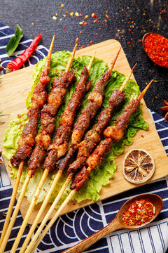 Grilled Lamb Kebabs on Wooden Board with Spices and Fresh Lettuce Garnish