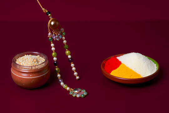 Designer Pearl Hanging Lumba Rakhi with Traditional Roli Chawal on Maroon Background