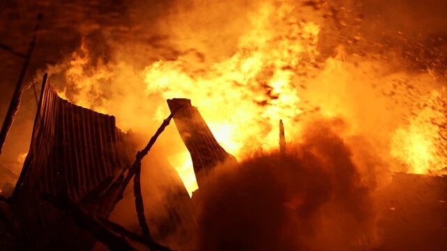 Khagrachari, Bangladesh - 06 March 2024: View of intense fire engulfing structures with massive flames and thick smoke at night.