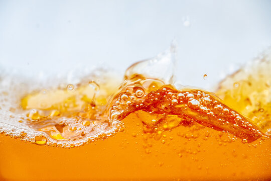 Close up of golden beer splashing with bubbles and foam in a glass, creating dynamic liquid movement. Refreshing alcoholic drink background for commercial beverage advertising and design