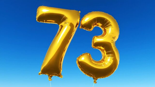 Celebrating Seventy-Three Years: Golden Foil Balloons Float Against a Clear Blue Sky