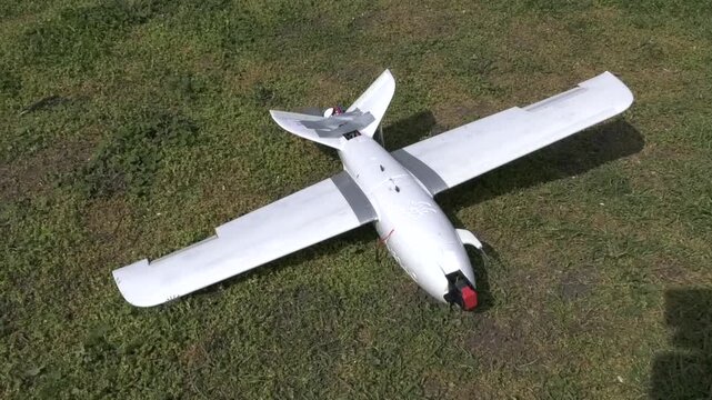 Aircraft-type attack drone positioned on grass and ready for launch during a military mission. Concept of unmanned aerial systems, modern warfare technology, and deployment of combat drones in wartime