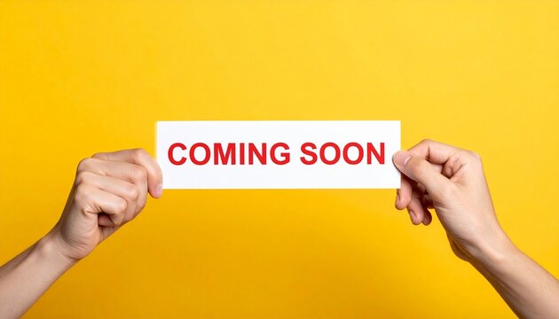 Hands holding card with coming soon text on yellow