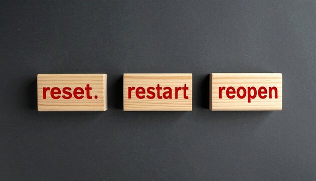 Wooden blocks showing reset, restart, reopen on dark surface