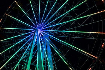 Fototapeta premium Nighttime Ferris wheel illuminated by colorful LED rings, wheel not moving