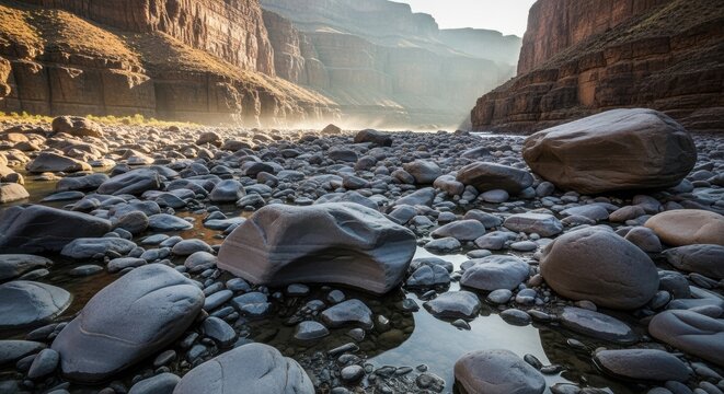 Boulder strewn riverbed in a vast sunlit canyon