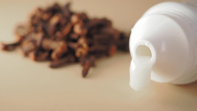 White Toothpaste Squeezing from Tube with Cloves in Background