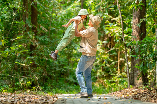 Happy Asian father carrying young daughter during tropical forest adventure, family parent and child enjoy outdoors active lifestyle travel nature exploration in woodland on summer holiday vacation.