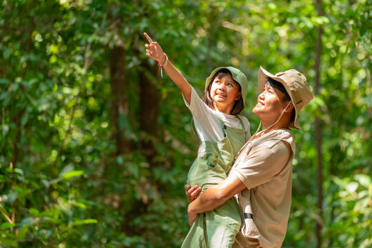 Happy Asian father carrying young daughter during tropical forest adventure, family parent and child enjoy outdoors active lifestyle travel nature exploration in woodland on summer holiday vacation.