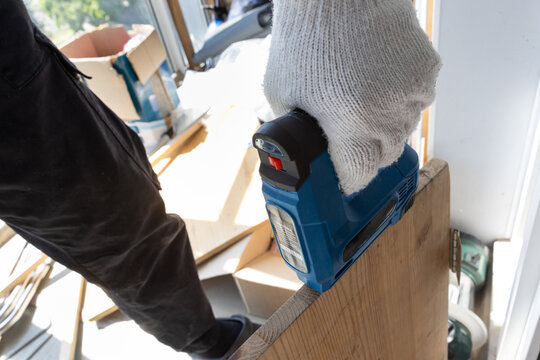 Compact electric tacker securing material to wooden frame near window