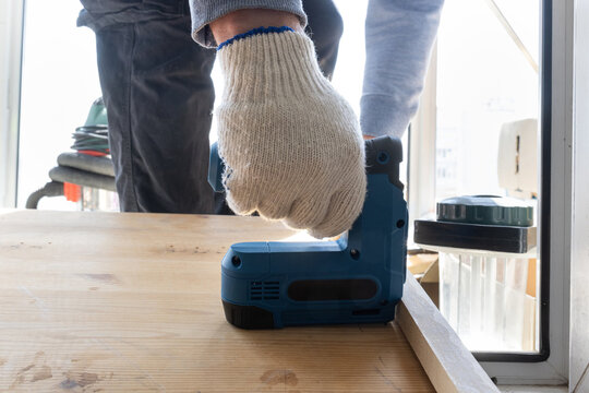 Handheld electric stapler attaching board edge during interior woodworking project