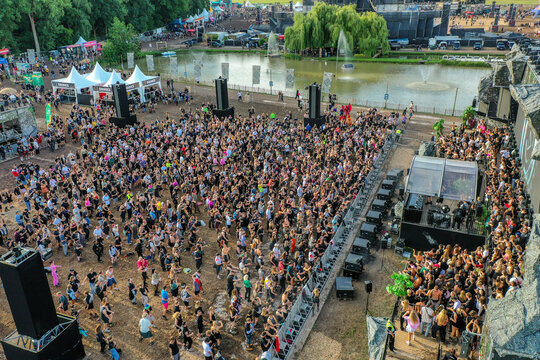 Herzogenaurach, Germany - 27 July 2025: Aerial view of Open Beatz Festival with a large crowd of people dancing near a stage and a pond with fountains.