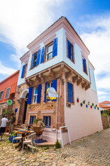 Fototapeta premium Ayvalik - Turkey, May 17, 2026, Historic Stone House with Vibrant Blue Shutters on Cunda Island in Ayvalik