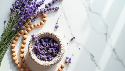 Fototapeta premium Crocheted bowl holds lavender sprigs near wood beads on marble surface. Top view composition suggests calm, wellness, spa, and natural craft. Peaceful atmosphere.