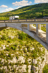Fototapeta premium Caravan visiting Verdon Gorge in French Alps with Chauliere Bridge over the Artuby river, France.