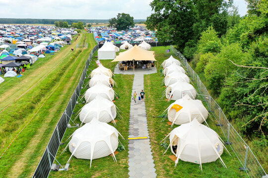 Herzogenaurach, Germany - 26 July 2025: Aerial view of the Open Beatz Festival glamping area with rows of white tents and a large tan canopy.