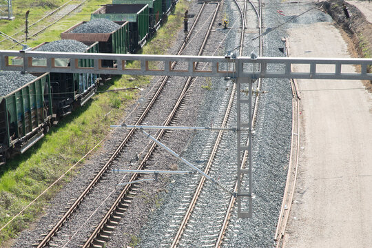 Overhead electric railway structure above old and newly rebuilt railroad tracks with freight wagons nearby.