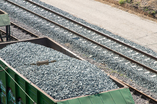 Close overhead view of freight wagons loaded with ballast gravel near modern railway tracks and rail infrastructure.