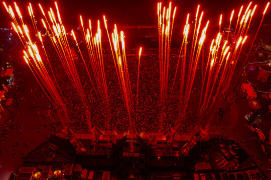 Herzogenaurach, Germany - 26 July 2025: Aerial view of Open Beatz Festival with a massive crowd and red fireworks illuminating the night sky.