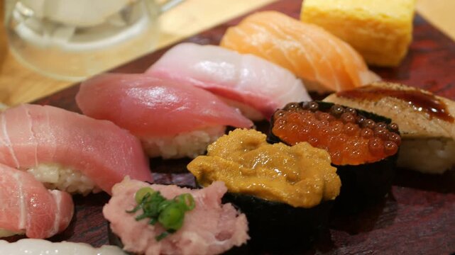 close up to A platter of assorted sushi nigiri with shrimp, fish, salmon and egg, presented on a wooden rectangular plate in japanese sushi style restaurant 