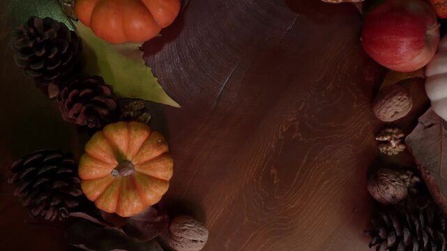 Seasonal pumpkin shaped border adorned with leaves and pinecones around text area. Festive wooden surface featuring pumpkin border decorated with seasonal leaves and pinecones surrounding text space