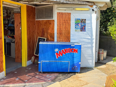 Venice, Italy - May 20, 2026: MAXIBON branded ice cream freezer outside a small shop with wooden walls and a bright yellow door in a sunny location