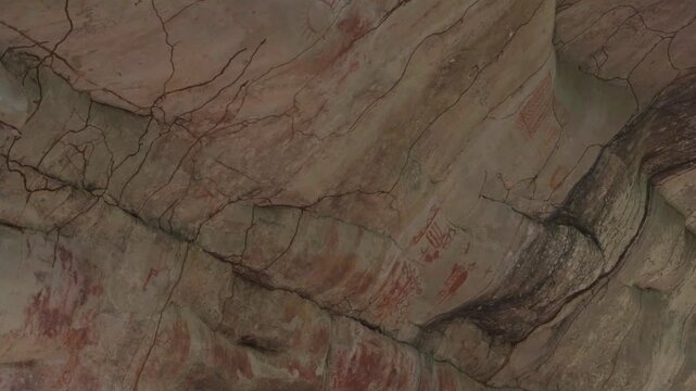 Intricate pictographs on rock face reveal ancient artistry and exposed stone formations in natural light.