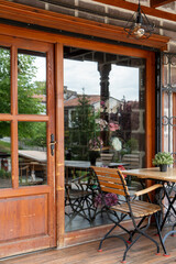 Fototapeta premium Artistic reflection of traditional Hamamönü houses on a cafe window, featuring wooden architecture, outdoor seating, and layered urban storytelling in Ankara, Turkey.