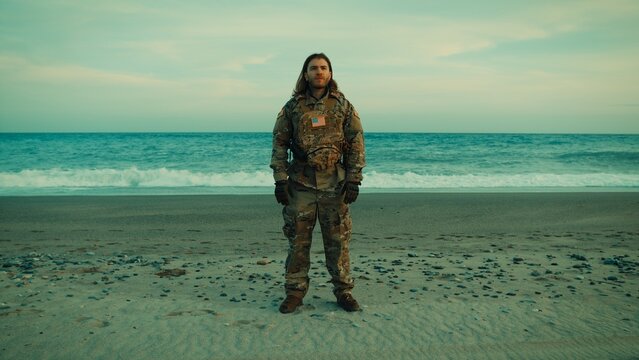 American Navy soldier performs a jumping jack exercise on the beach near ocean