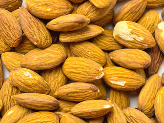 Fototapeta premium Pile of raw almonds shown in close up with visible texture and natural warm tones. Healthy snack ingredient