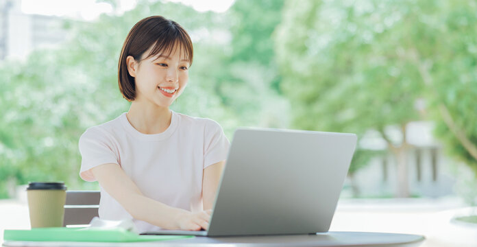 テラスでパソコンを使う若い女性