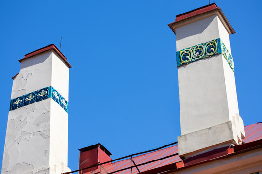Old house chimneys and a red metal roof with vents