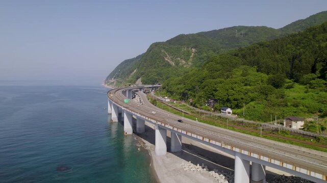 トンネルとS字カーブから後退しながら海岸線の全貌を現すダイナミックな空撮