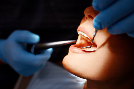 Close up of professional dental examination using mirror and scaler during oral healthcare procedure