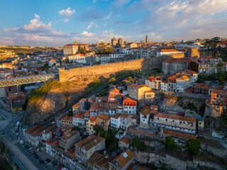 Drone view of Ribeira in Porto, Portugal, with Dom Luis I Bridge edge, hillside streets, and warm morning light © Dmitry Rukhlenko