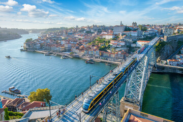 Obraz premium Elevated view of Porto and Ribeira with a tram on Dom Luis I Bridge and tourist boats on the Douro River in Portugal